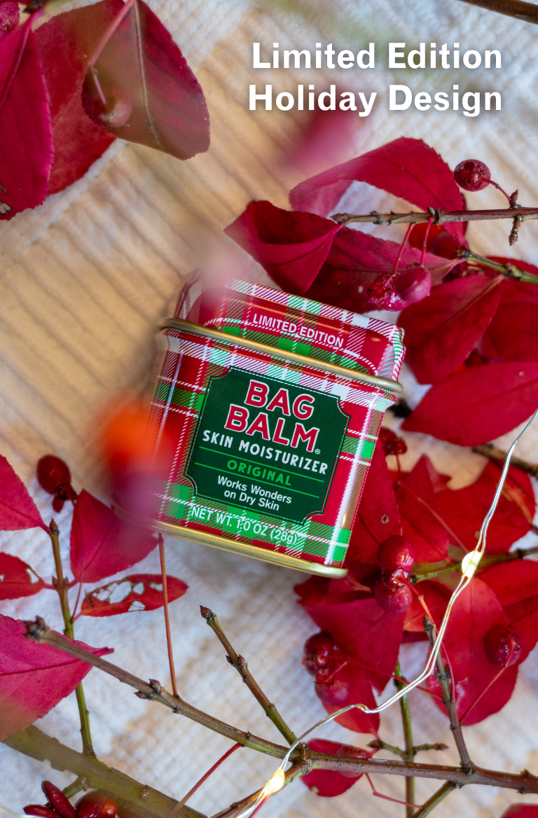 Bag Balm skin moisturizer with a limited edition holiday design surrounded by red leaves and branches.