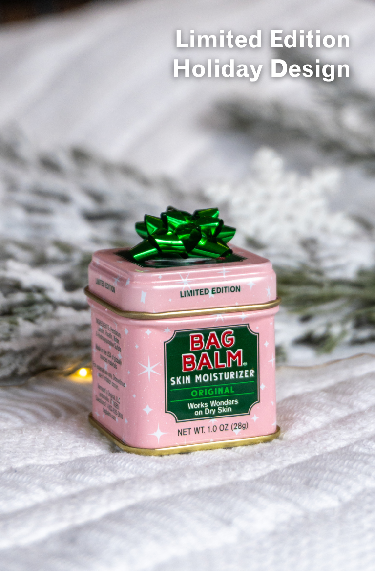 Pink tin of Bag Balm skin moisturizer with a green bow on a white background