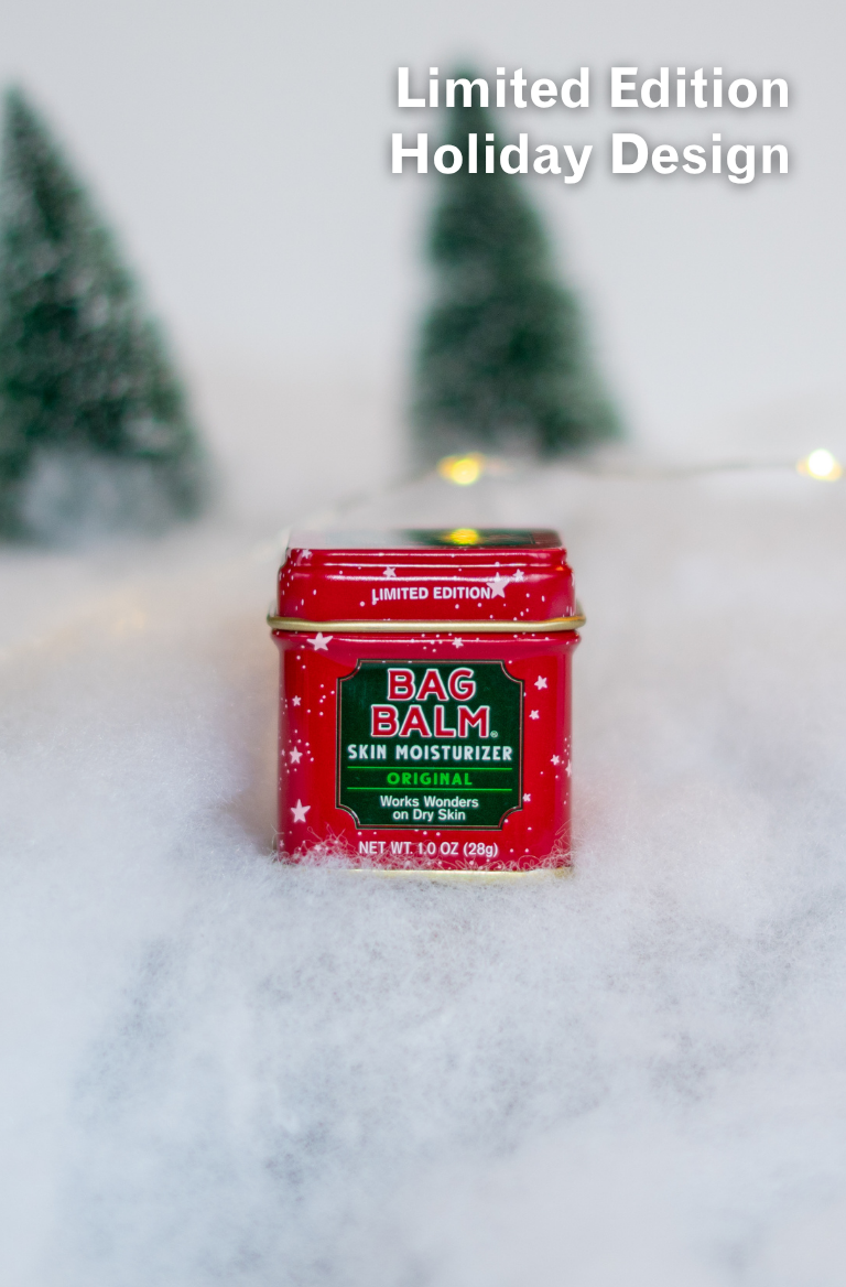 Red tin of Bag Balm with Christmas trees and lights in the background