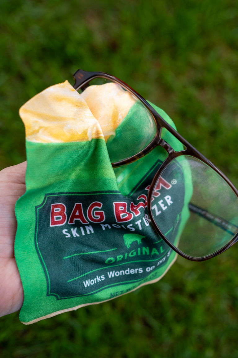 A glasses wipe shaped like a Bag Balm tin wiping glasses