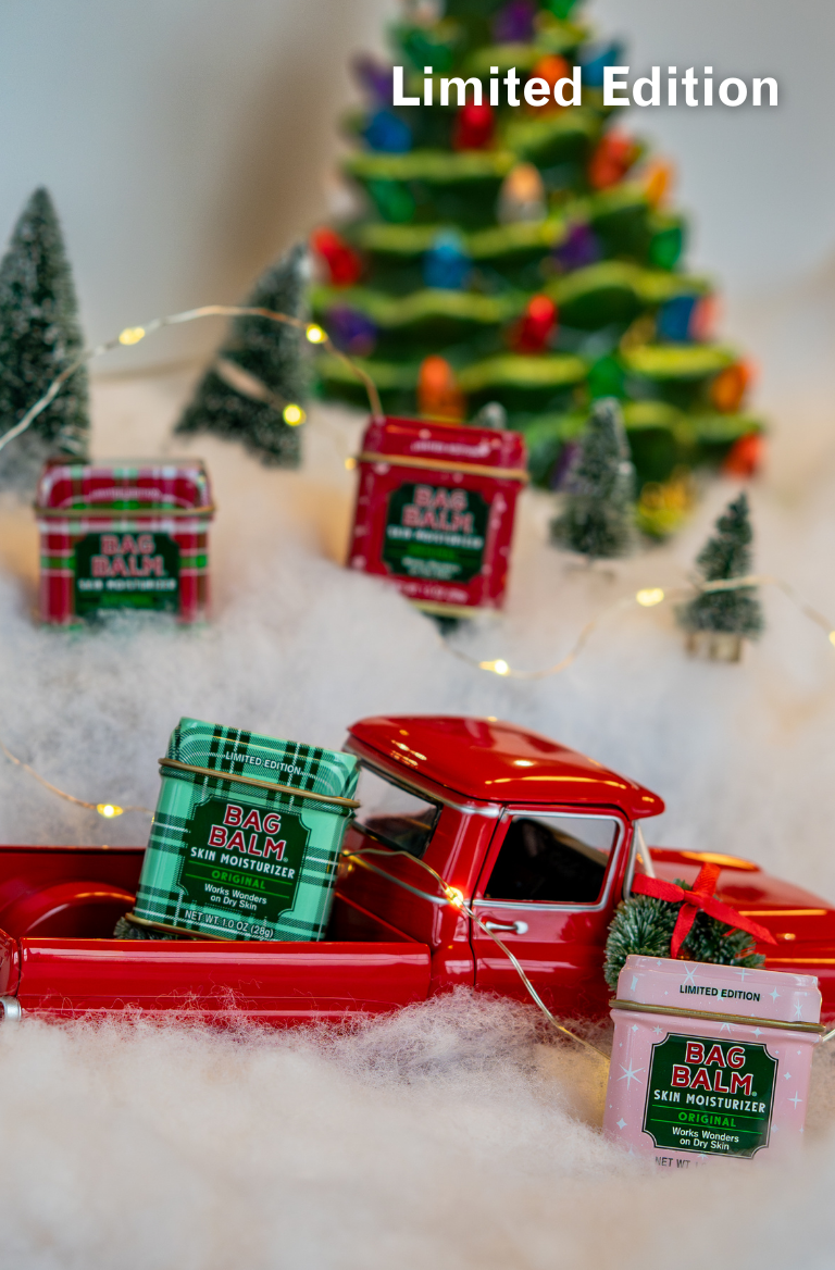Red toy truck with Bag Balm containers in a festive setting with Christmas trees and lights.