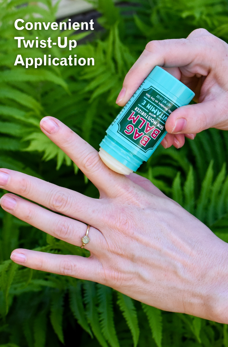 Person applying a stick of Balm to their hand with greenery in the background