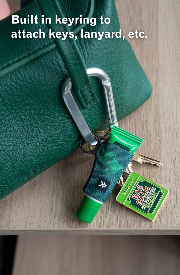 Green keychain with carabiner attached to a green bag on a wooden surface.