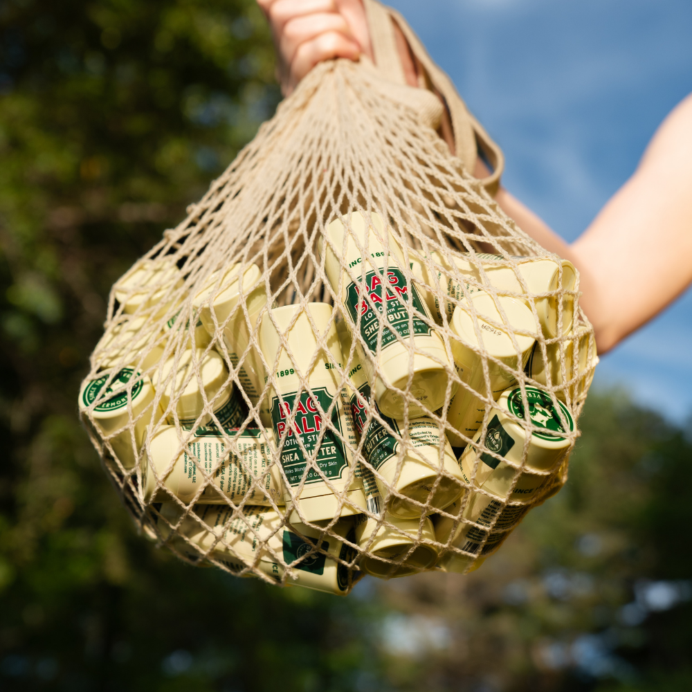 Net bag filled with Bag Balm lotion sticks against a natural background