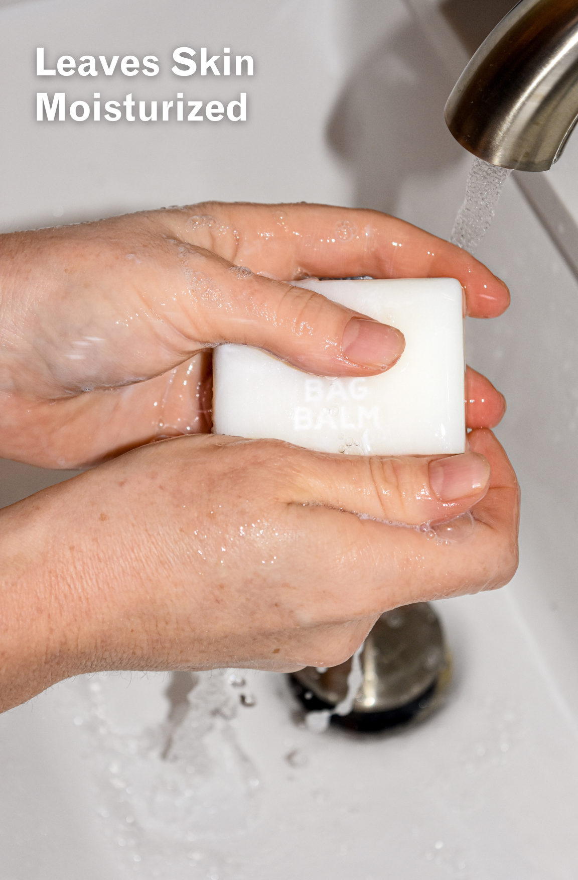Hands under running water holding bar of soap