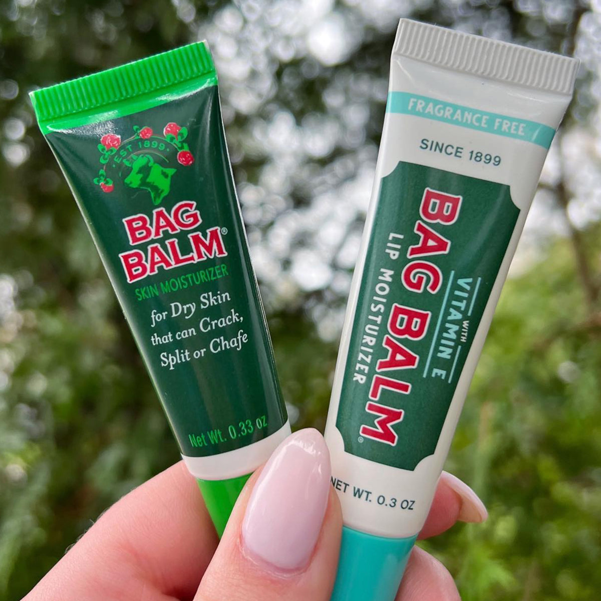 A person holding two tubes of Bag Balm Lip Moisturizer and Bag Balm Skin Moisturizer