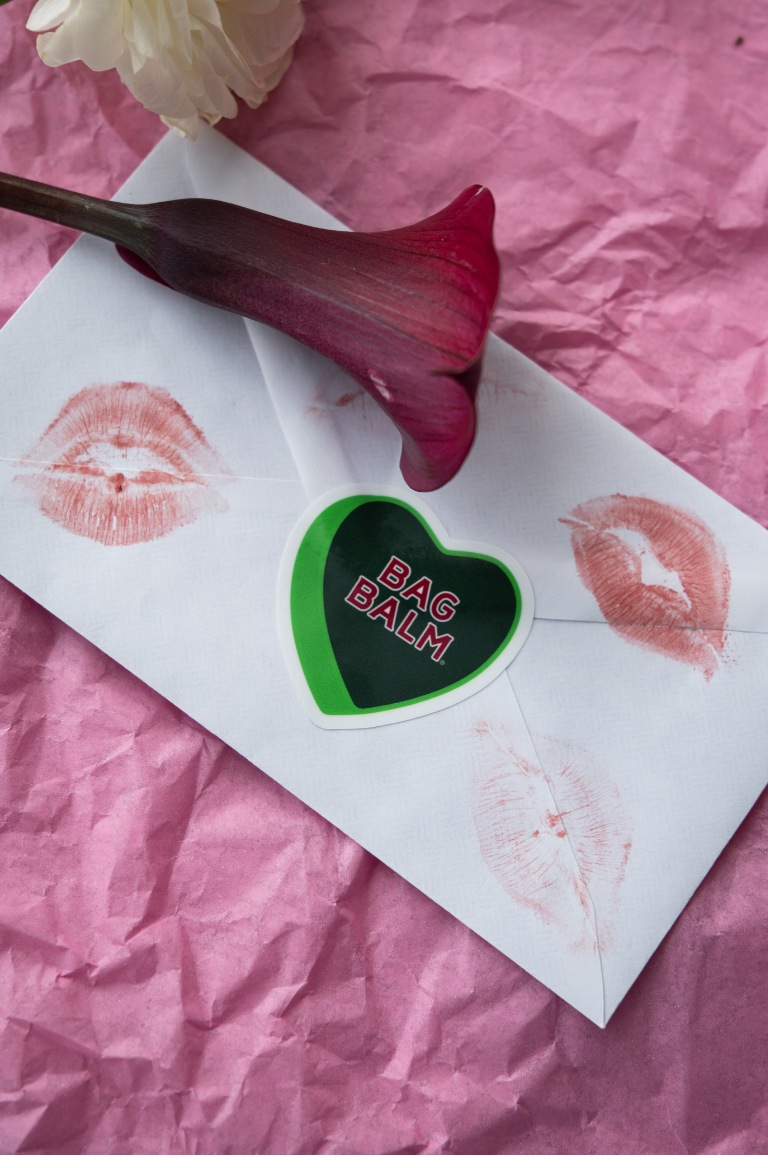 Heart-shaped bag balm sticker on an envelope with lipstick prints