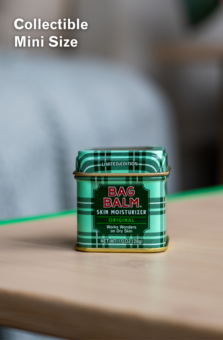 Green tin of Bag Balm skin moisturizer on a wooden surface with a blurred background