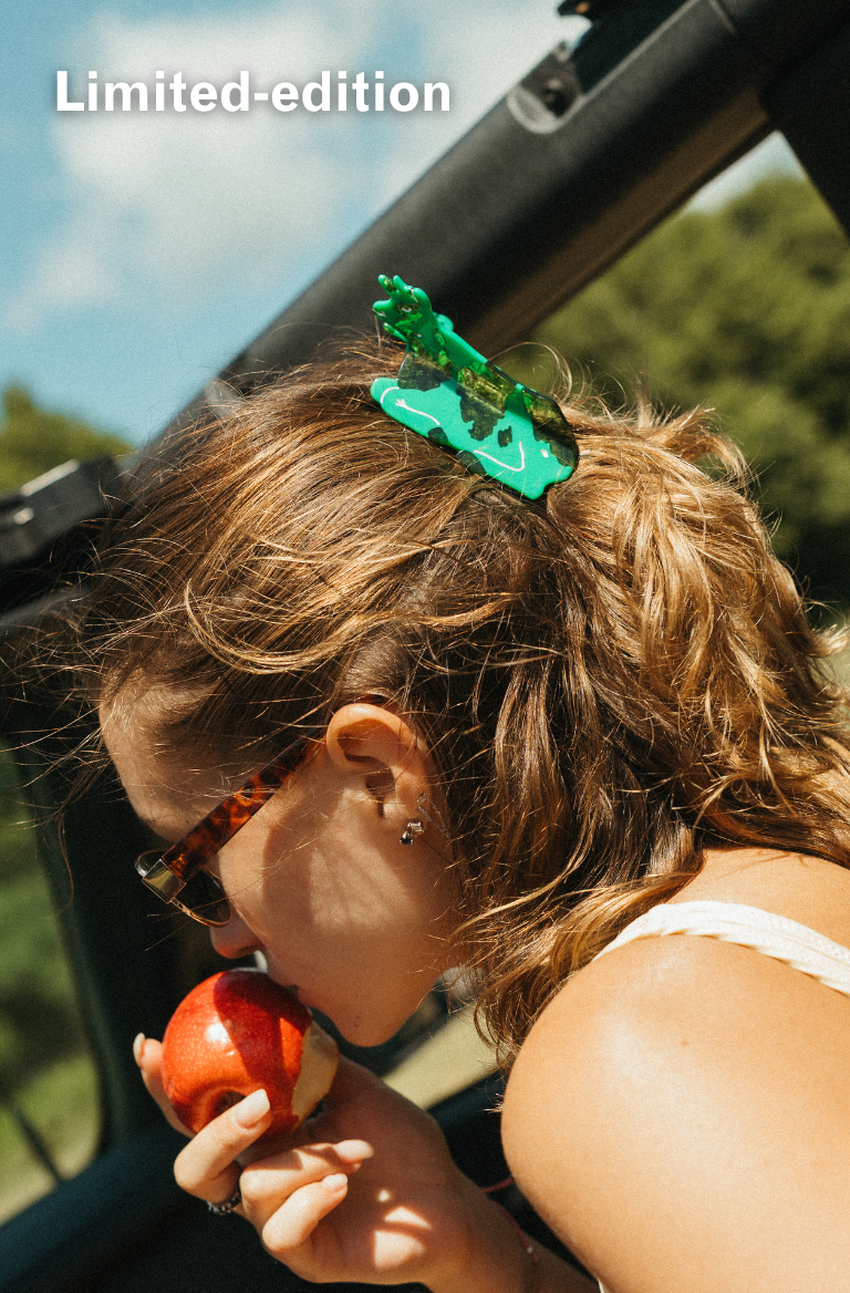 Woman in car holding an apple wearing Green Cow shaped hair claw clip.