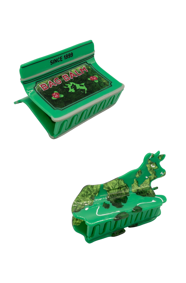Two green novelty hair claw clips shaped like a Bag Balm Tin and A green cow.