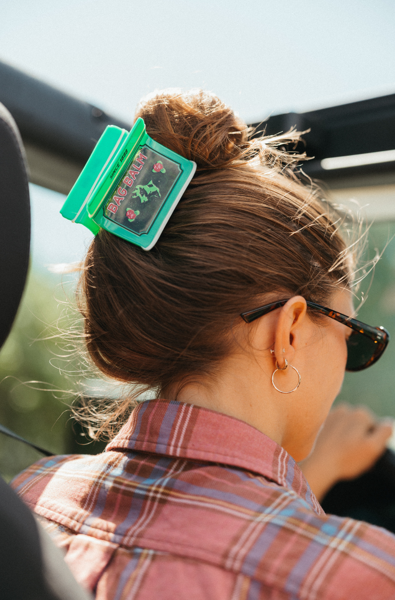 A woman in a car wearing a Bag Balm tin shaped hair claw clip