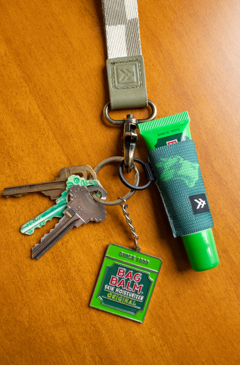 Keychain with Bag Balm tube, key, and tag on a wooden surface