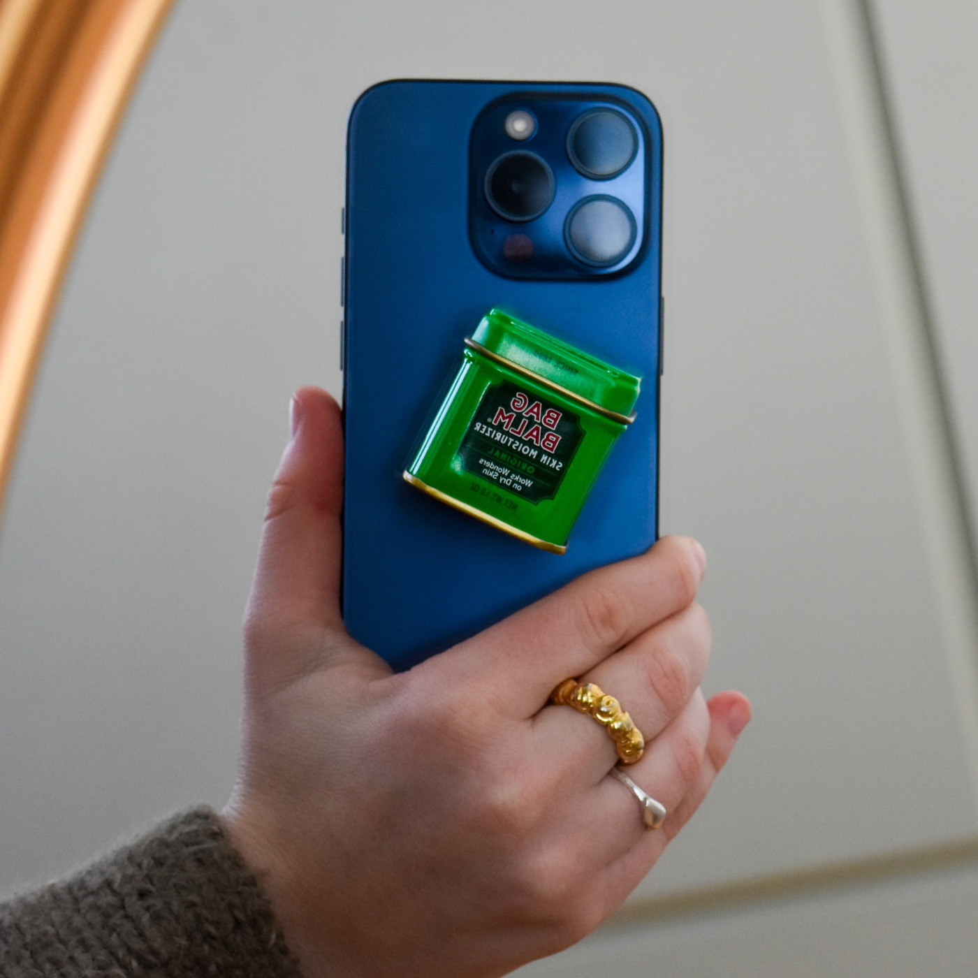 A green Bag Balm pop socket on a blue cell phone case