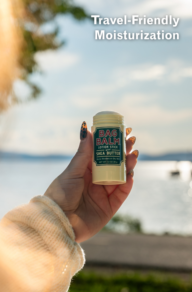 Hand holding a Bag Balm lotion stick with a scenic background