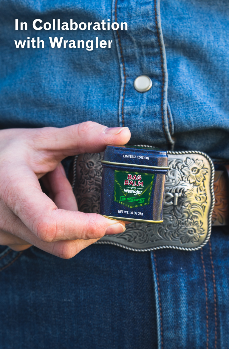 Limited Edition Denim Design Bag Balm 1oz tin in collaboration with Wrangler in front of western belt buckle