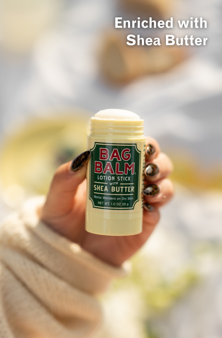 Hand holding a Bag Balm lotion stick with a blurred background
