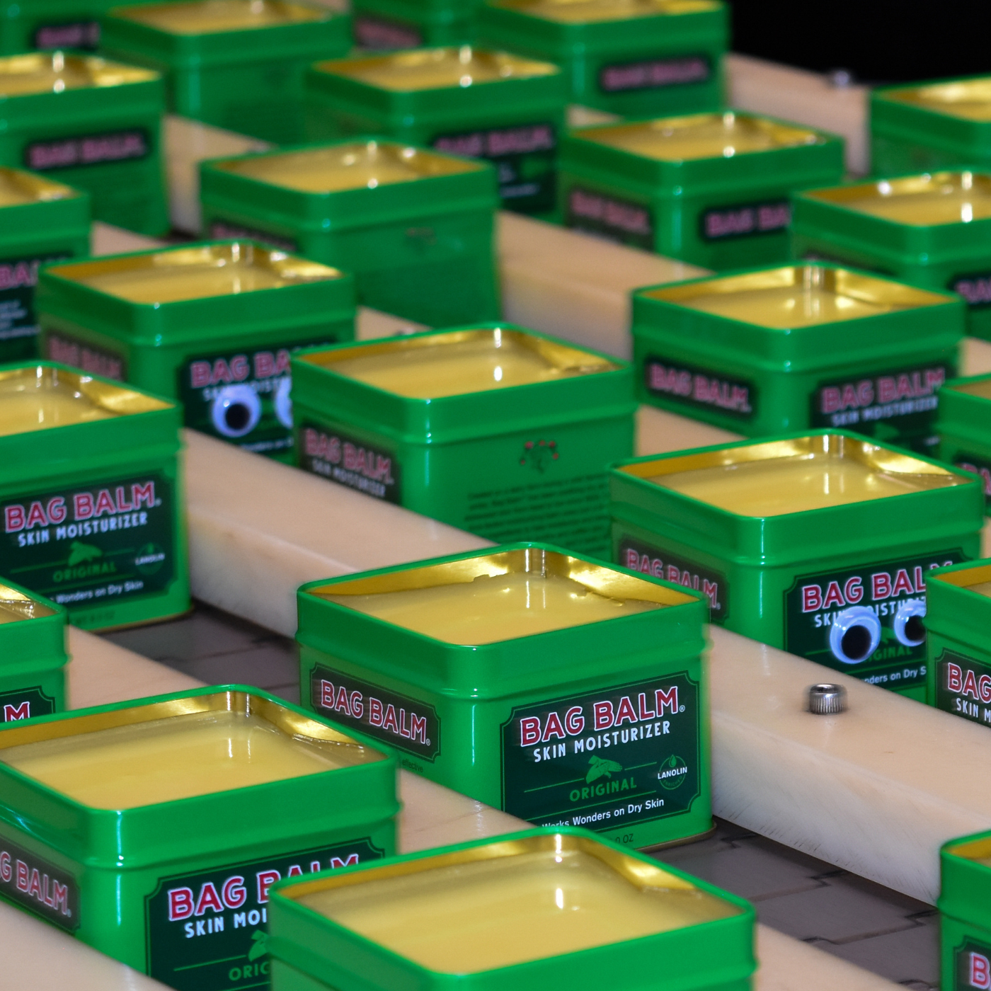 Image of many open green tins of Bag Balm in a factory