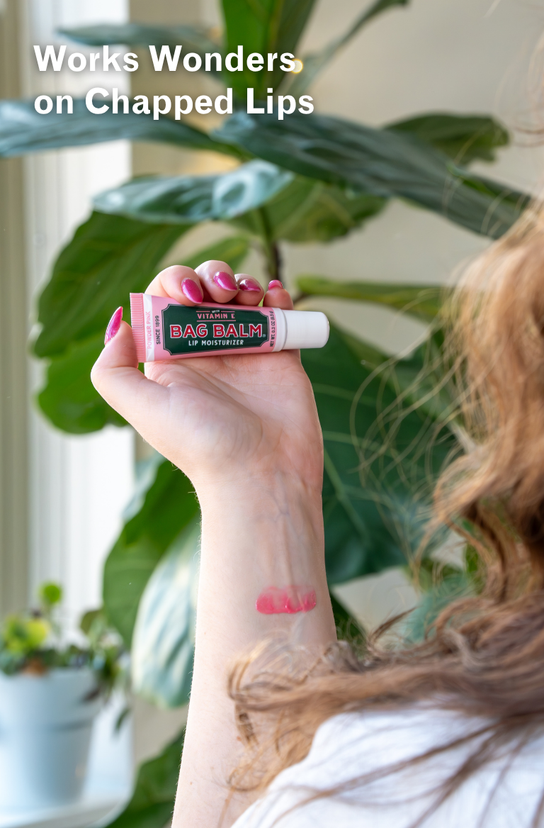 Hand holding a lip balm with text 'Works Wonders on Chapped Lips' and a plant in the background.