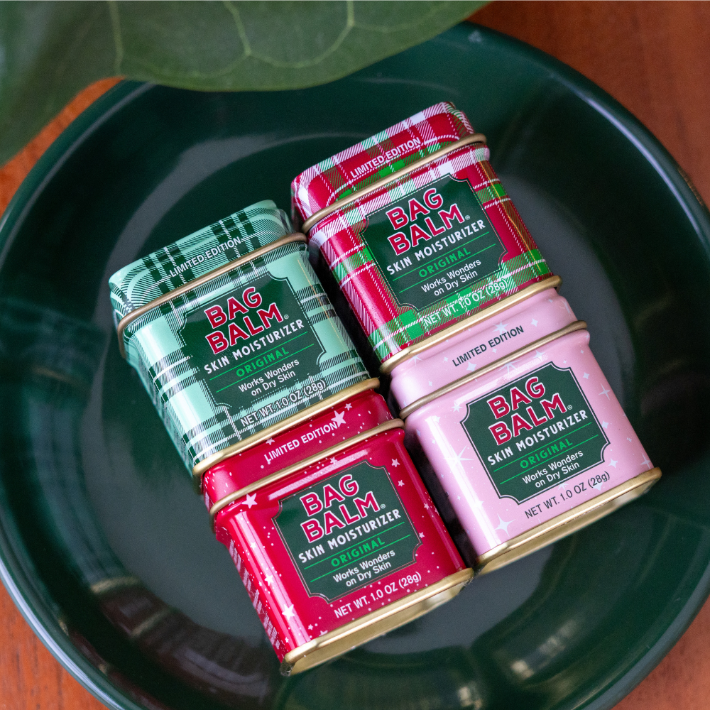 Four tins of Bag Balm skin moisturizer on a green plate.